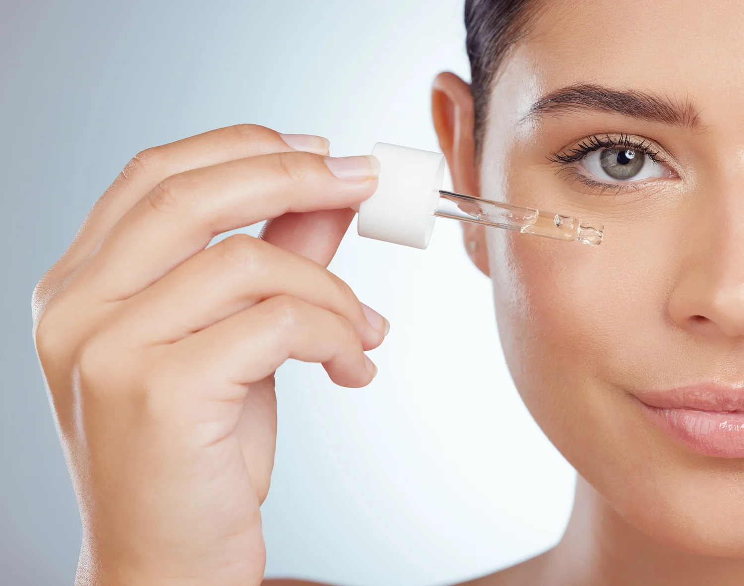 Woman using a serum dropper on her face